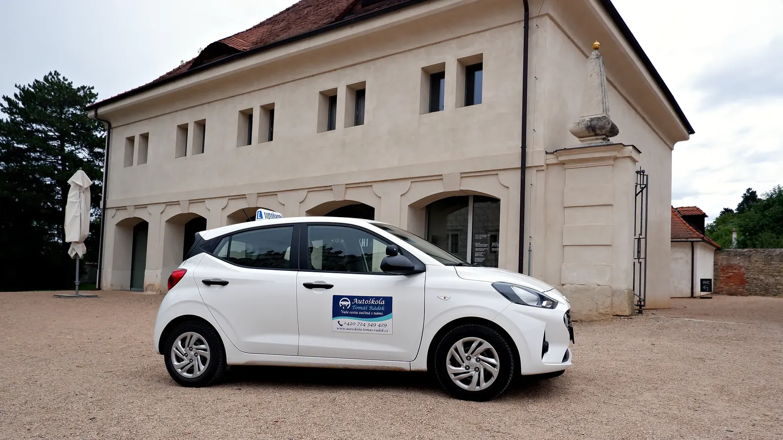 Hyundai i10 autoškoly z&nbsp;boku na nádvoří před Kočárovnou